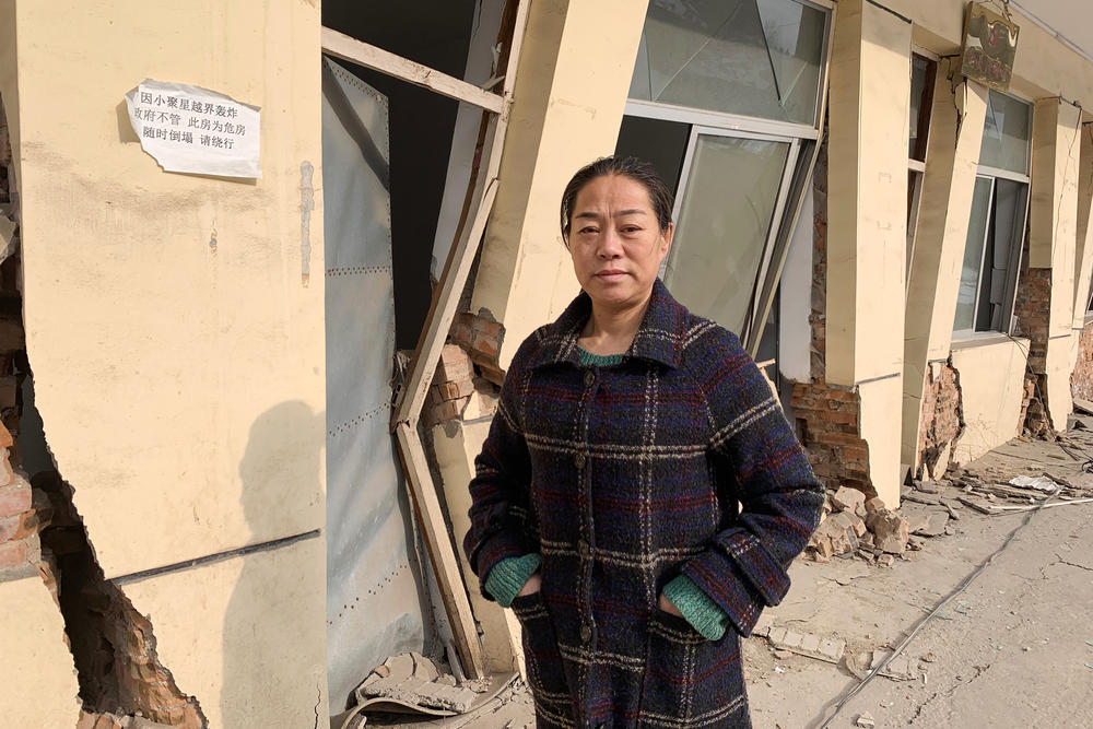 Zhang Xiaohui, the sister of Zhang Zhixiong, in front of Juxin Mining offices. The building and much of the mine collapsed because of tunneling from nearby mines.