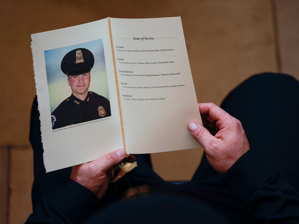 A Capitol Police officer holds a program as people pay their respects at the remains officer Brian Sicknick, who died after defending the Capitol against the Jan. 6 insurrection.