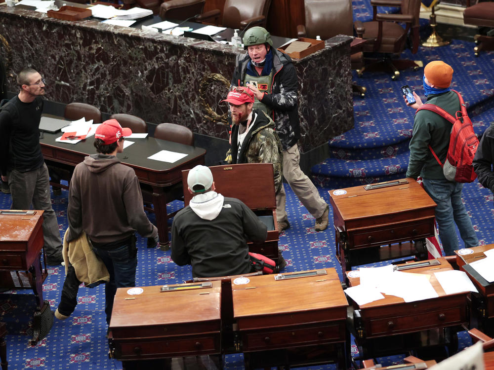 Bruno Cua, 18, is allegedly seen here with his back to the camera, holding a tan jacket. Prosecutors say he entered the Senate Chamber of the U.S. Capitol on Jan. 6 with a handful of other rioters.