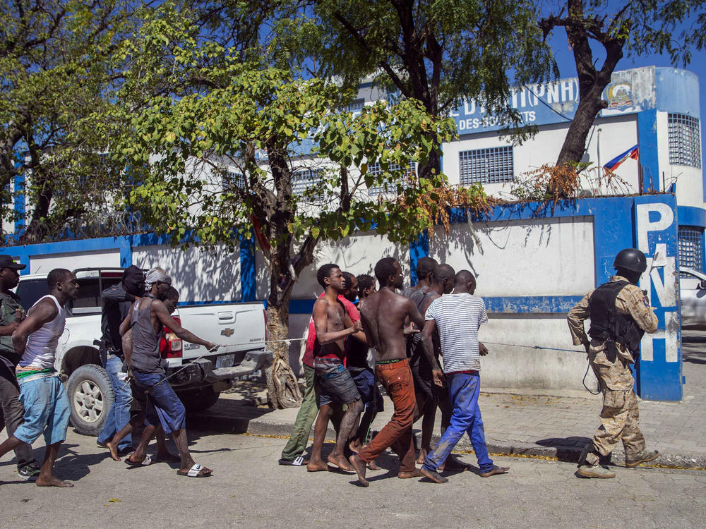 Police escort recaptured inmates back to the Croix-des-Bouquets Civil Prison after Thursday's outbreak in Port-au-Prince, Haiti. As of Friday night, authorities were still searching for more than 200 escapees.
