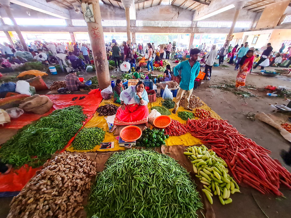 Farmers, traders and customers weave through waist-high heaps of chili peppers, piles of ginger and mounds of carrots at a government-run wholesale market in western India.