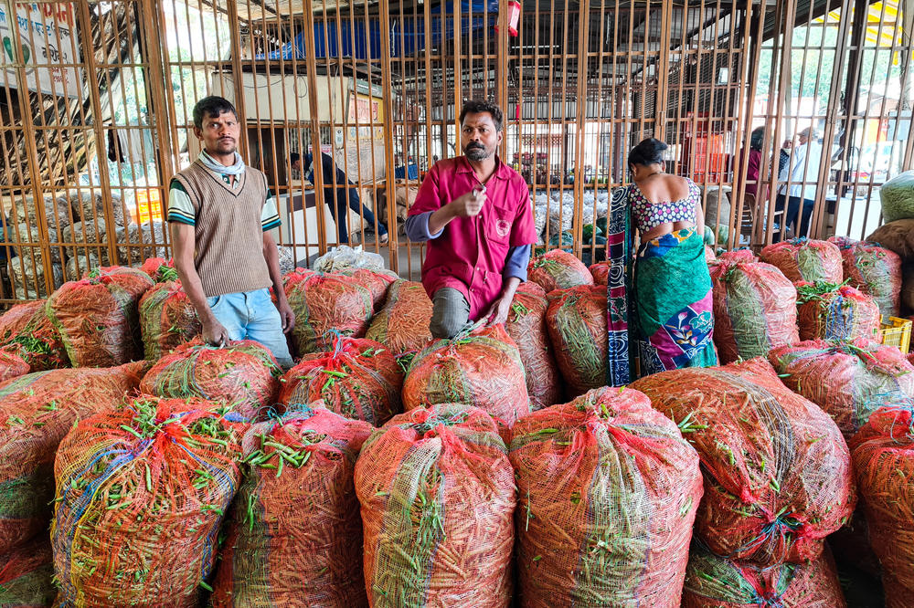Sacks of green beans, onions and carrots sit in a wholesale trader's office outside a government-run vegetable market in western India. Small traders fear new agriculture reforms, which have sparked huge protests in New Delhi, will obliterate middlemen like them.