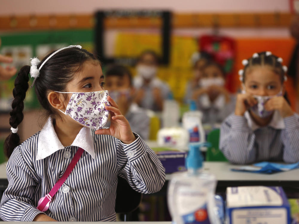 Palestinian elementary school students wearing protective face masks take their seats in their classroom amid the coronavirus pandemic on the first day of class in September at a United Nations-run school in the West Bank city of Ramallah.