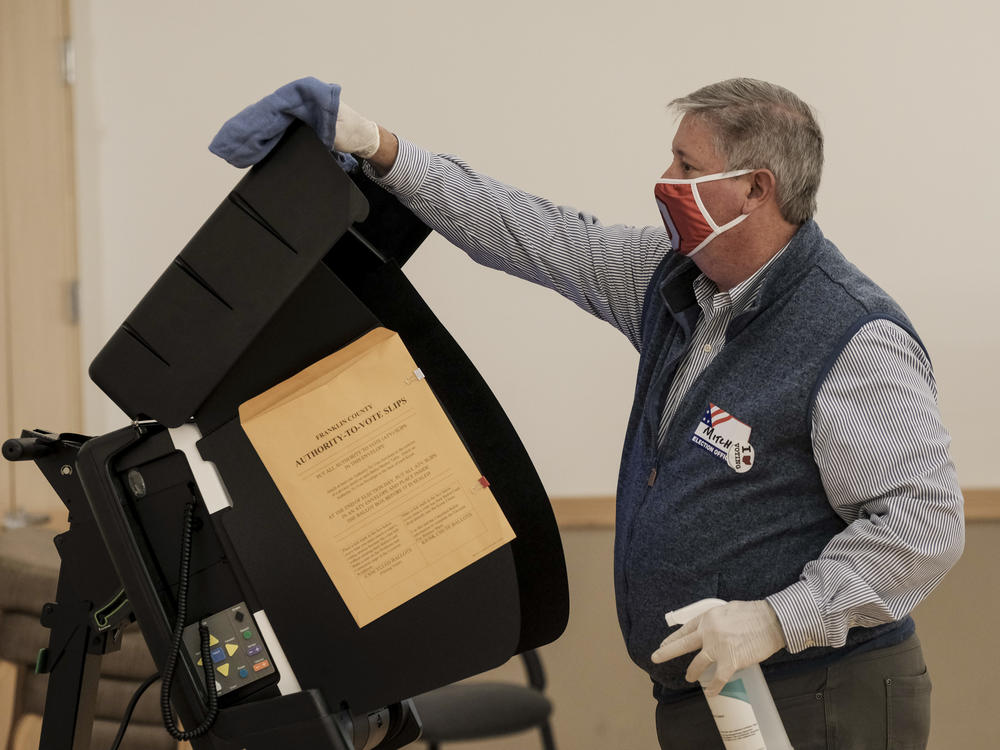 A poll worker sanitizes a voting machine on Nov. 3, 2020 in Columbus, Ohio. Conspiracy theories floated by former President Donald Trump about equipment made by Dominion Voting Systems has led local officials in one Ohio County to slow down the purchase of new Dominion machines.