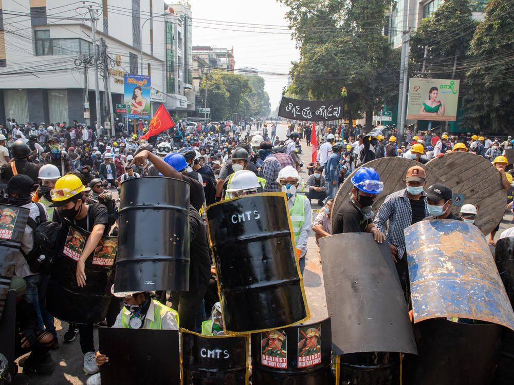 Demonstrators take shelter and block the road during a protest against the military coup in Mandalay, Myanmar on Wednesday.