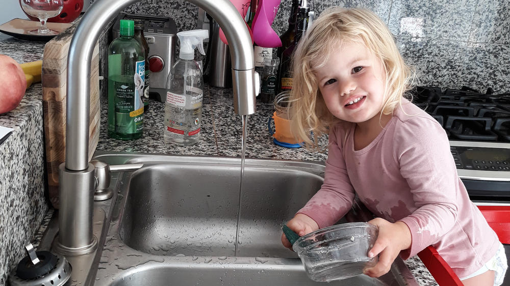 The author's daughter, Rosy, at age 2 as she does dishes — voluntarily. Getting her involved in chores did lead to the kitchen being flooded and dishes being broken. But she is still eager to help.