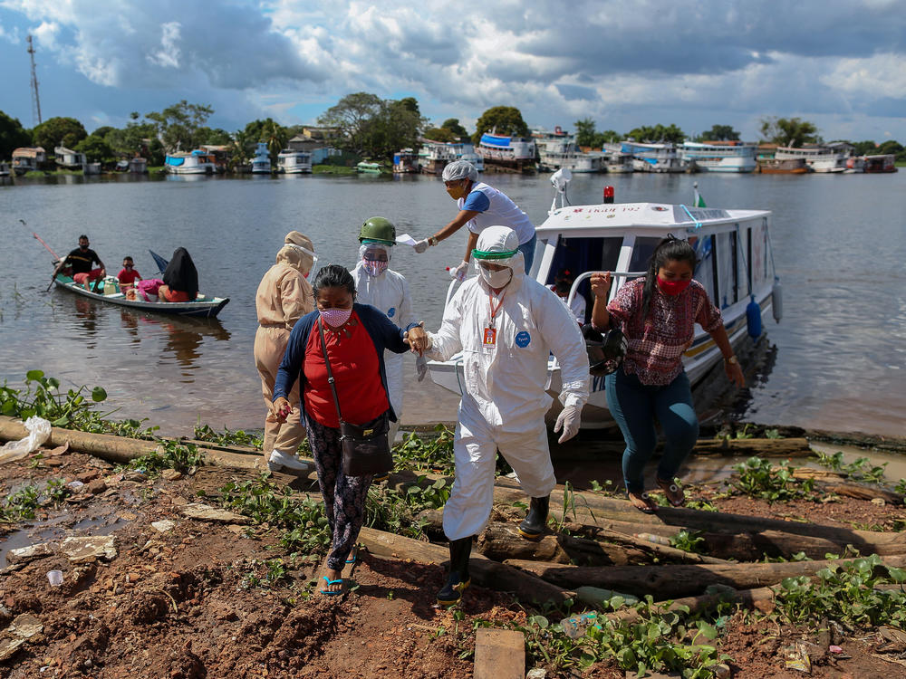 A surge in cases and record high daily death tolls have pushed Brazil into a COVID crisis. Above: Health professionals help patients with symptoms of the new coronavirus on a boat ambulance.