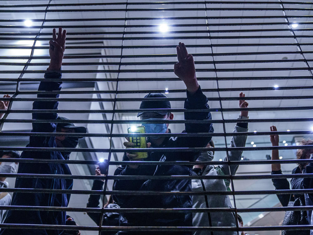Pro-democracy demonstrators gesture with three-fingered salutes outside West Kowloon Magistrates Courts during a hearing for opposition activists charged with violating the city's national security law in Hong Kong Thursday, March 4, 2021. All 47 of the pro-democracy activists in a Hong Kong subversion case returned to custody Thursday after a marathon hearing ended with them being denied bail.