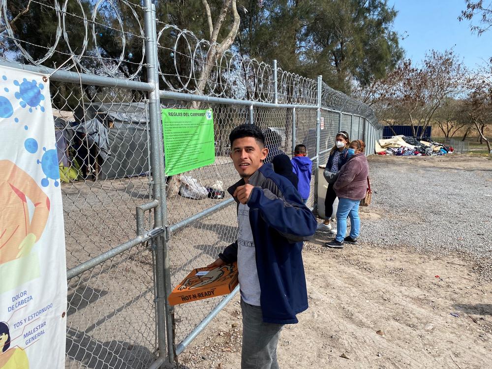 Danilo Peraza, 28, from Honduras, takes a pizza to his tent in the nearly empty migrant camp in Matamoros, Mexico. Most of the other migrants in the camp have been admitted into the U.S. but Peraza was left behind because his asylum case was rejected.