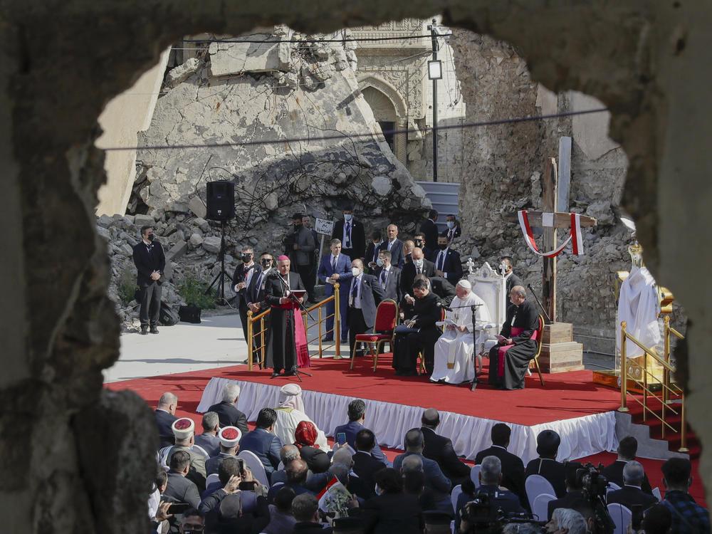 Pope Francis, surrounded by shells of destroyed churches, listens to Archbishop of Mosul Najib Mikhael Moussa during a gathering to pray for the victims of war at Hosh al-Bieaa Church Square, in Mosul.