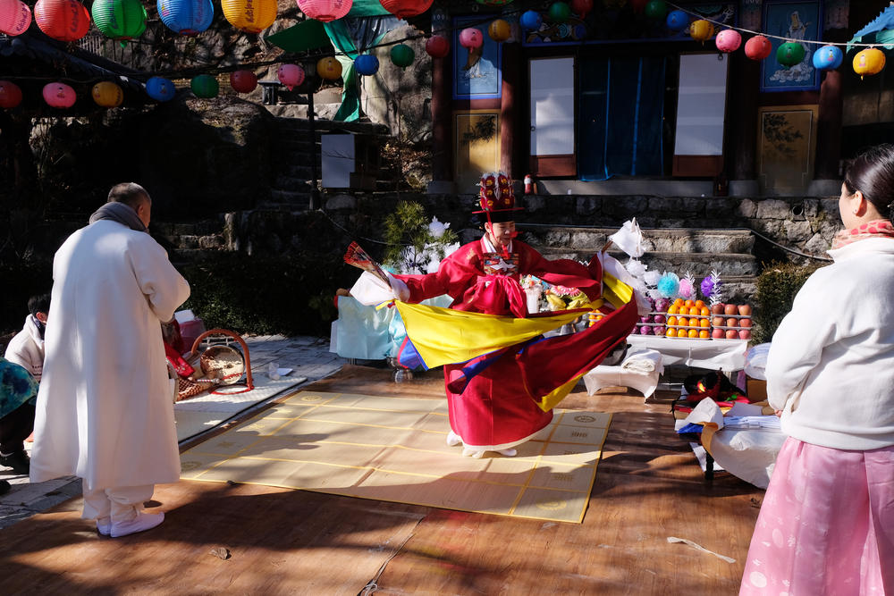 Shaman Jeong Soon-deok  (center) dances during the initiation ceremony for a new shaman (left) at a temple in Seoul.
