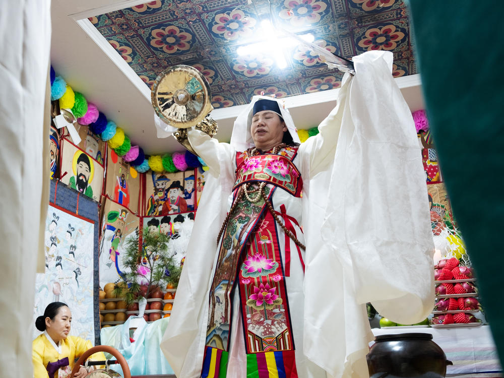 Shaman Jeong Soon-deok holds up a fan, bells and other ceremonial objects during an initiation ceremony at a temple in Seoul.