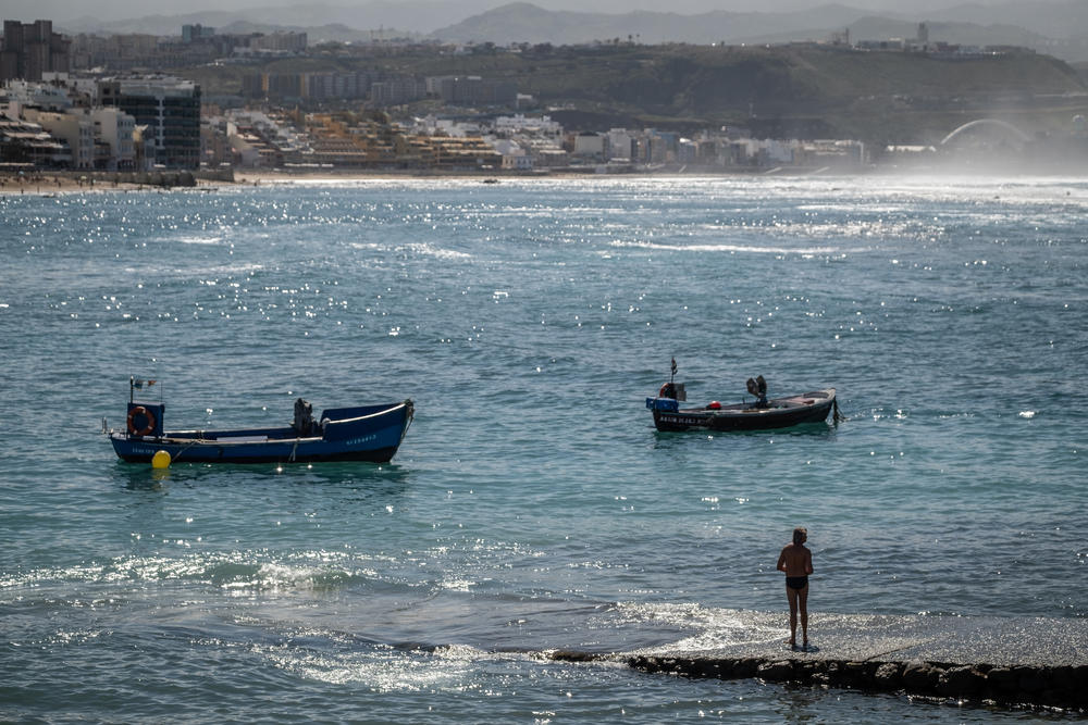 A man enjoys the sun on the small pier at Las Canteras beach in Las Palmas.