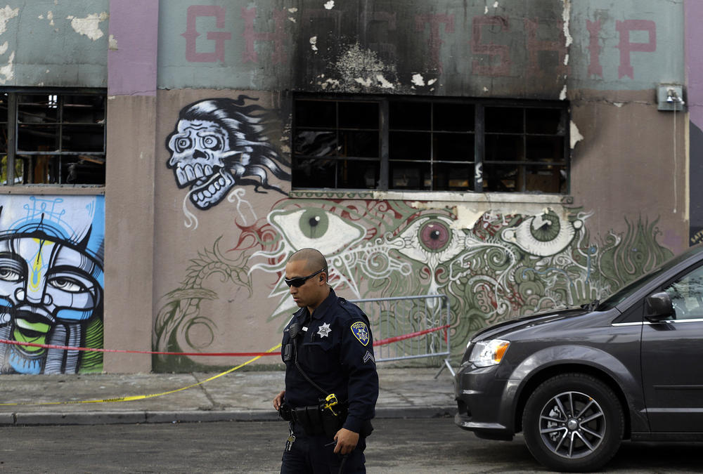 An Oakland police officer guards the area in front of the Ghost Ship in the aftermath of the fire.