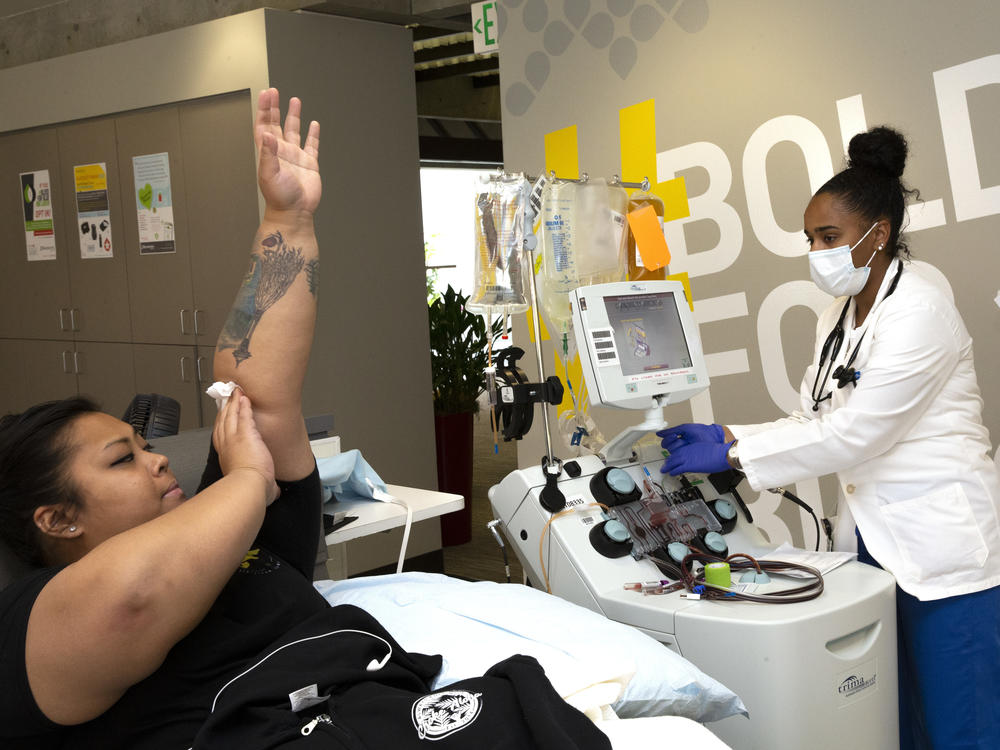 Melissa Cruz elevates her arm after donating COVID-19 convalescent plasma in April 2020 as phlebotomist Jenee Wilson shuts down the collection equipment at Bloodworks Northwest in Seattle.