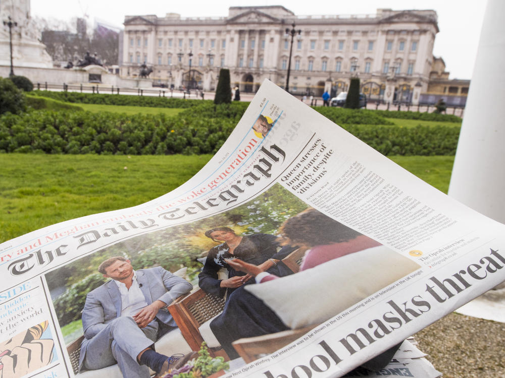 A British newspaper flutters in the wind outside Buckingham Palace in London the day after the Duke and Duchess of Sussex's interview with Oprah Winfrey.