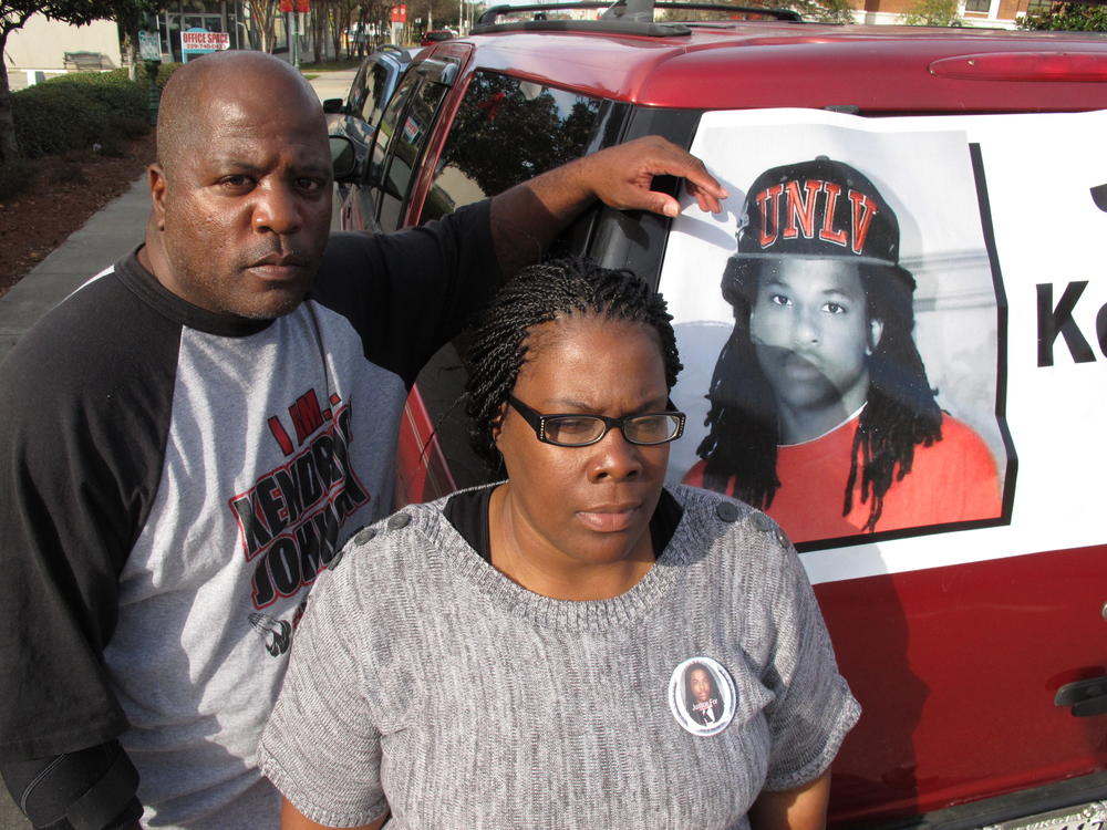 Kenneth and Jacquelyn Johnson stand next to a banner on their SUV showing their late son Kendrick, in Valdosta, Ga., in December 2013. A family spokesperson told NPR they are 