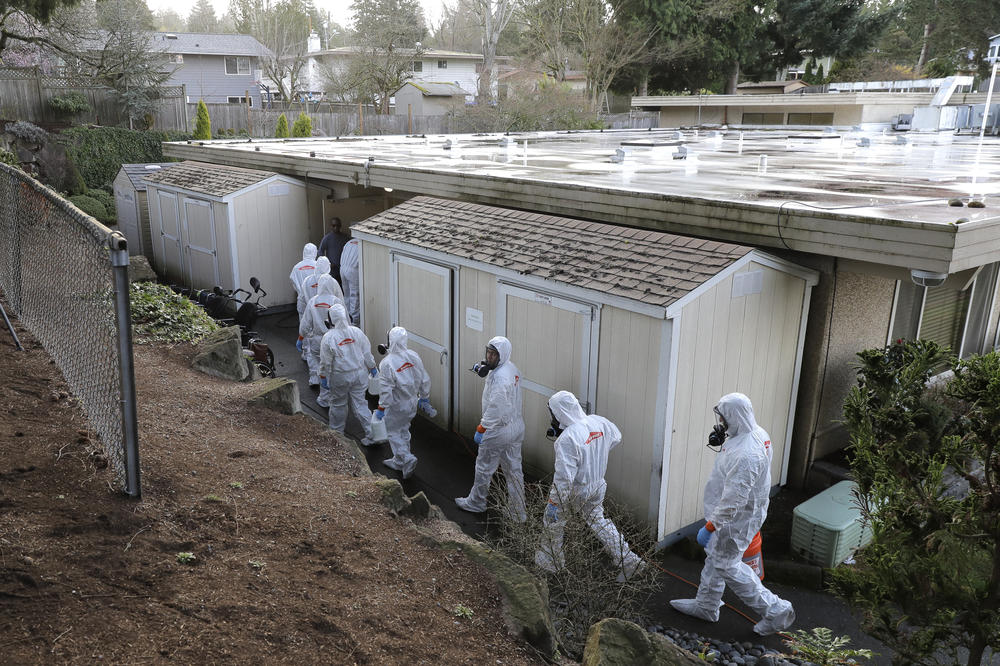 Workers from a Servpro disaster recovery team wearing protective suits and respirators enter the Life Care Center in Kirkland, Wash., to begin cleaning and disinfecting the facility on March 11, 2020.