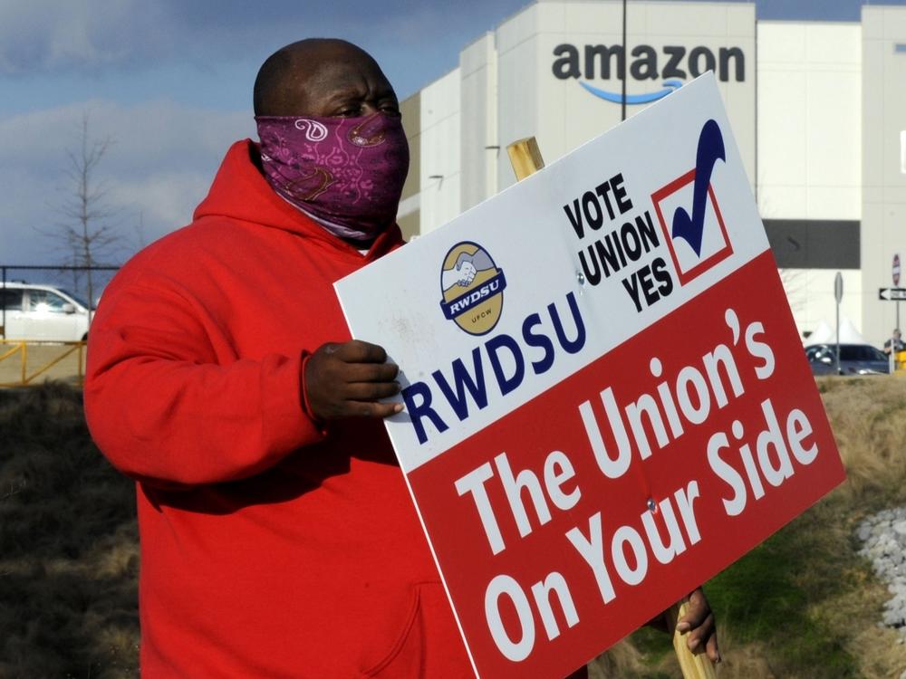 Michael Foster of the Retail, Wholesale and Department Store Union holds a sign outside an Amazon warehouse in Bessemer, Ala., where workers are voting on whether to unionize.