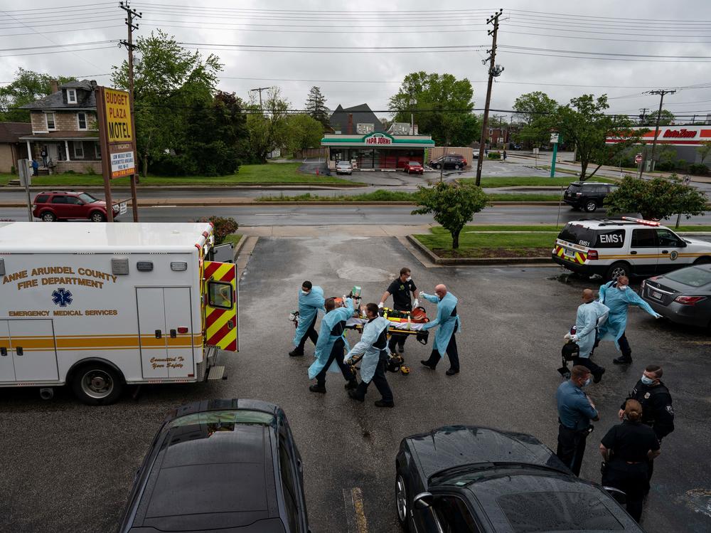 Firefighters and paramedics with the Anne Arundel County Fire Department in Maryland wear enhanced PPE, during the coronavirus pandemic, as they transport a patient after responding to a call for a cardiac arrest as a result of a drug overdose on May 6, 2020.