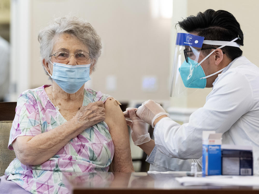 A CVS pharmacist gives the Pfizer/BioNTech COVID-19 vaccine to a resident at the Emerald Court senior living community in Anaheim, Calif., in January. Federal health officials have revised advice on nursing home visitations for the first time since September.