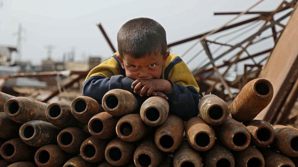 A Syrian child poses atop a stack of neutralized shells at a metal scrapyard on the outskirts of Maaret Misrin town in the northwestern Idlib province, Syria last week.
