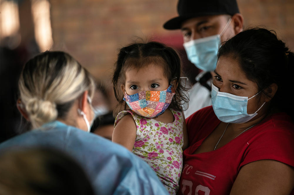 A mother holds her daughter while awaiting COVID-19 test results last month after being released by U.S. immigration authorities in Brownsville, Texas.