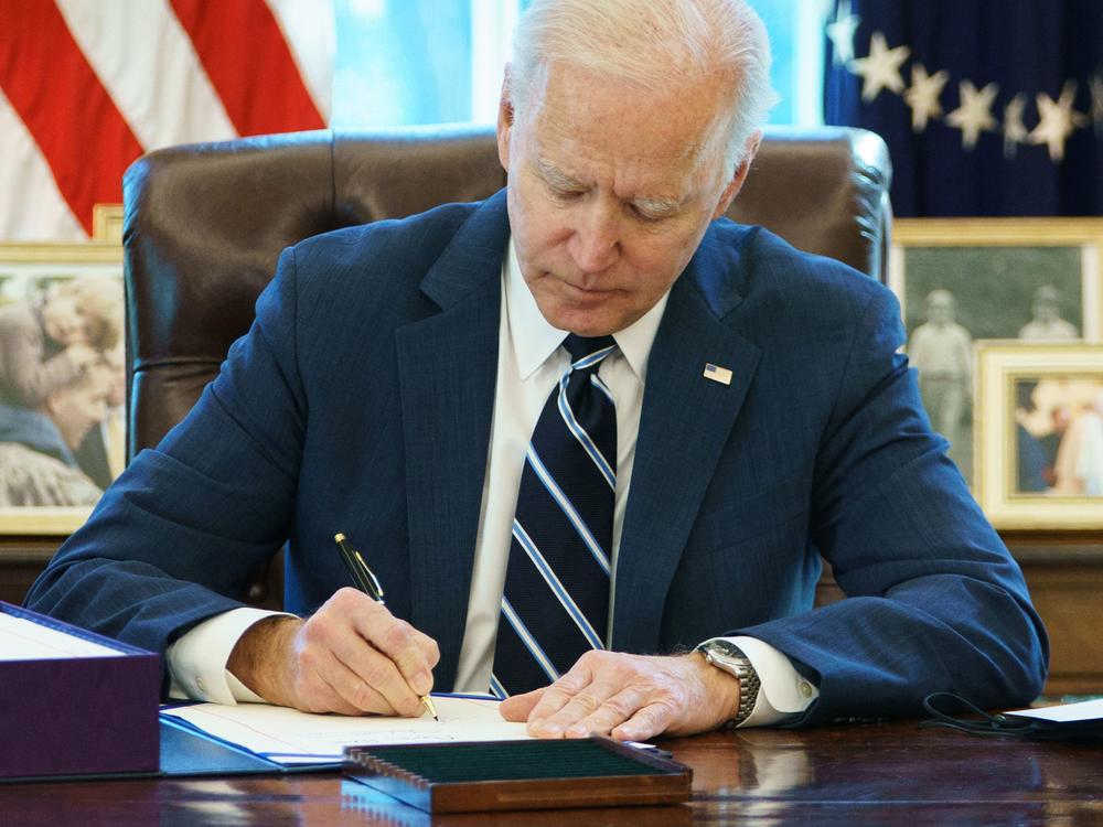 President Biden signs the American Rescue Plan Thursday in the Oval Office. The $1.9 trillion economic stimulus bill includes $1,400 stimulus checks for most Americans.