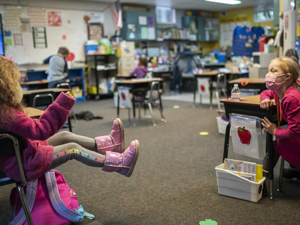 Two first grade students talk in the back of class at the Green Mountain School last month in Woodland, Wash. The CDC's current guidance for schools recommends seating or desks be 