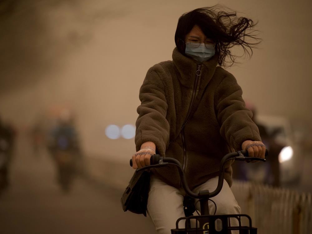 A woman cycles along a street during a sandstorm in Beijing on Monday.