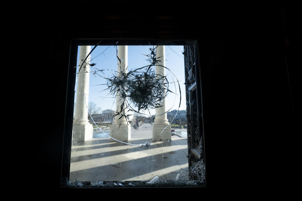 The pillars of the U.S. Capitol are seen through a shattered window on Jan. 7, the day after the riot.