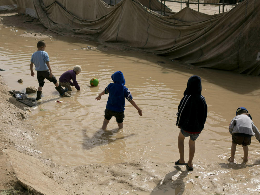 In this March 31, 2019 file photo, children play in a mud puddle in the section for foreign families at al-Hol camp in Hasakeh province, Syria.