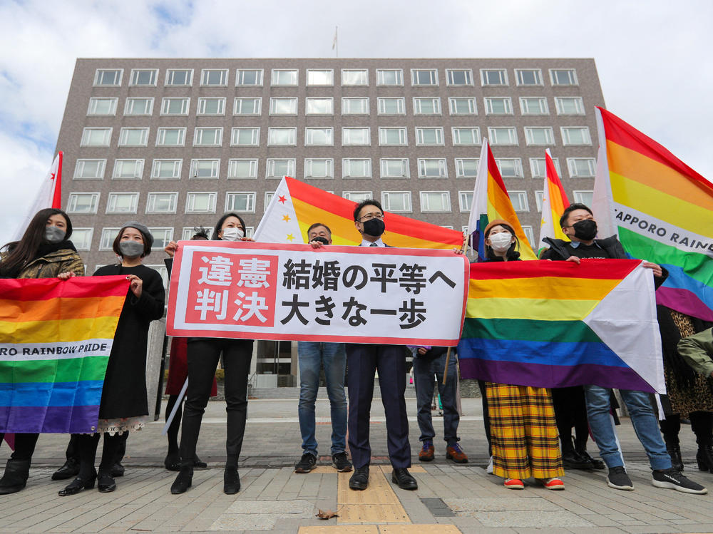 Supporters celebrate the district court's ruling on Japan's same-sex marriage ban with a flag reading 