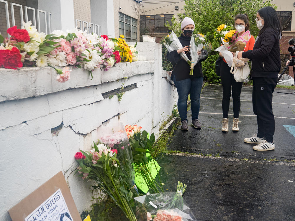 Mourners visit and leave flowers on Wednesday at the site of two shootings at spas across the street from one another in Atlanta.