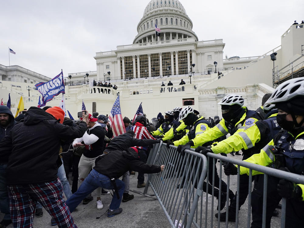 In January, rioters, including many with ties to white supremacists, try to break through a police barrier at the Capitol in Washington.