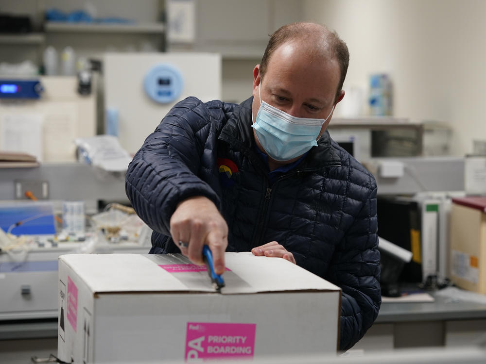 Colorado Gov. Jared Polis opens the shipping box containing the state's first shipment of COVID-19 vaccine at the Colorado Department of Public Health and Environment, Dec. 14, 2020, in east Denver.