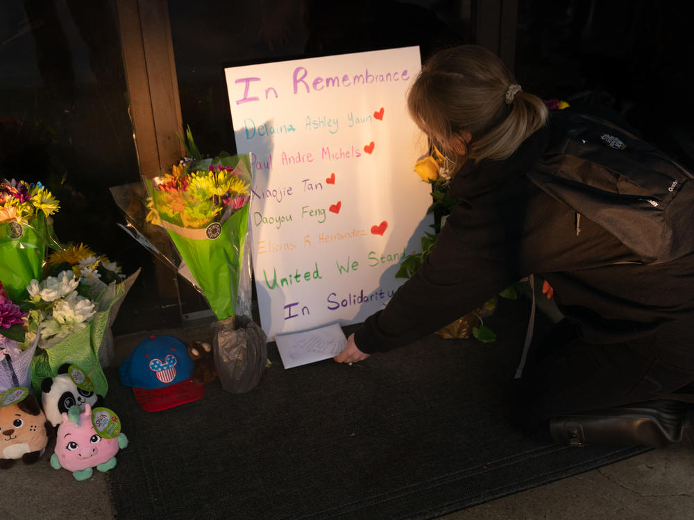 Shelby Swan places a sign outside Youngs Asian Massage, where four people were shot and killed this week in Acworth, Ga. Another four people were fatally shot at two massage businesses in Atlanta, but authorities have not released their names.