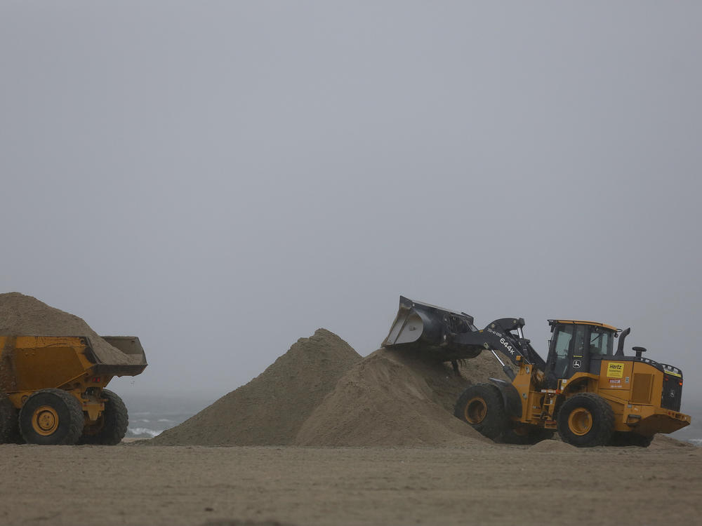 A front-end loader and dump truck move beach sand to protect vulnerable areas from flooding in Southern California in 2016.