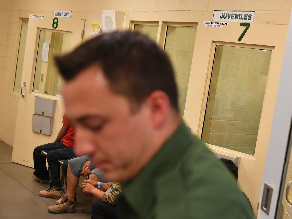 In this file photo, young migrants, whose faces cannot be shown, sit inside a U.S. Customs and Border Protection Facility in Tucson, Arizona.