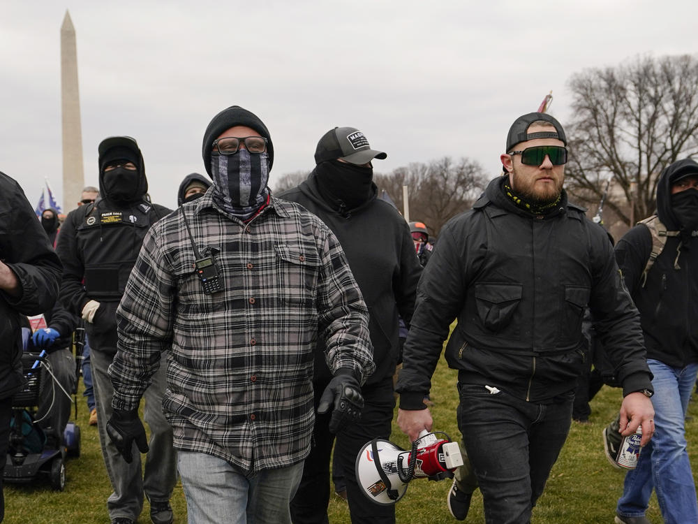 Proud Boy members Joseph Biggs (left) and Ethan Nordean, carrying a megaphone, walk toward the U.S. Capitol on Jan. 6. They were among four people indicted over conspiring to attack the Capitol.