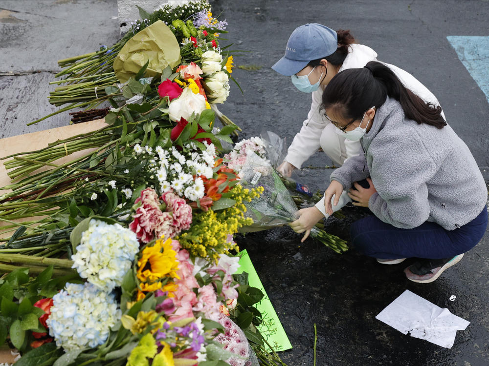 Jenny Choi (left) and Kristi You place flowers Wednesday at the entrance of Gold Spa, one of three locations where deadly shootings happened in the Atlanta area this week.