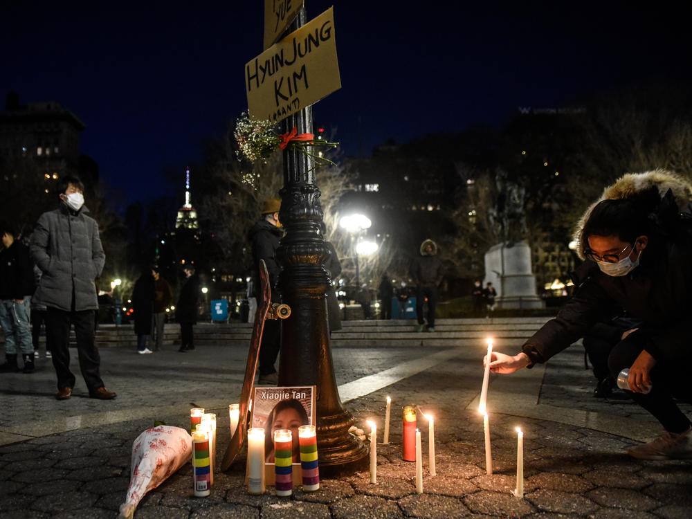 A mourner lights candles for the victims of Tuesday's shootings in Atlanta at a vigil in New York City, one of many across the country this week.