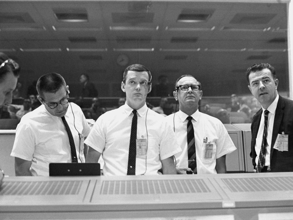 Viewing the Gemini 10 flight display in the Mission Control Center on July 18, 1966 are (from left) Mission Director William Schneider, Prime Flight Director Glynn Lunney, Flight Operations Director Christopher Kraft Jr. and Gemini Program Manager Charles Mathews.