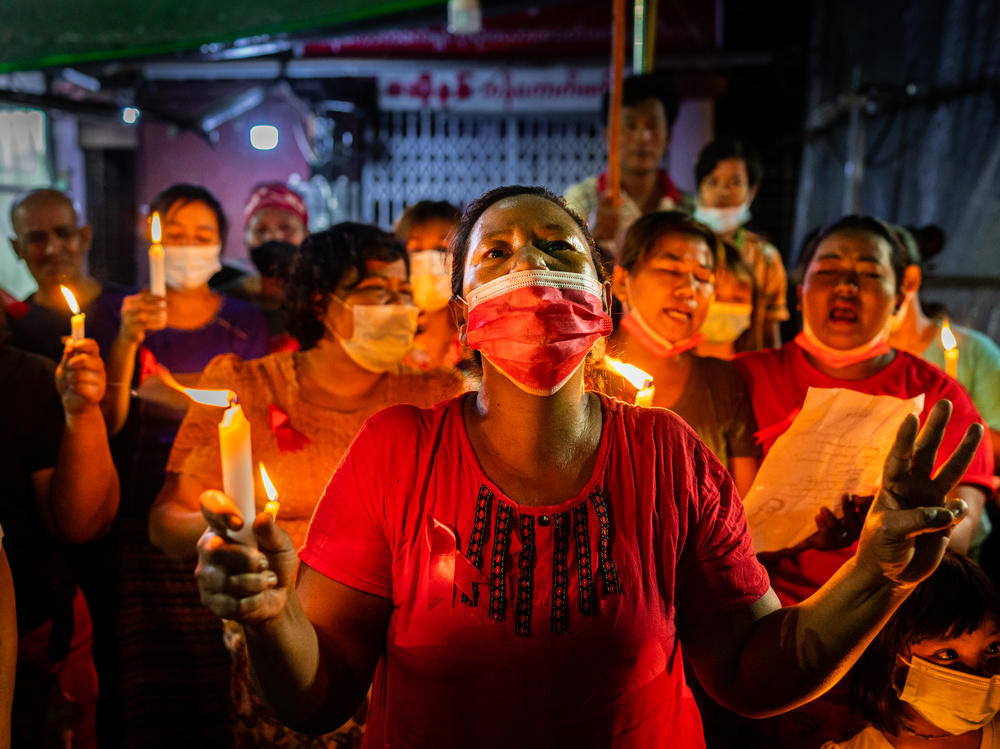 People hold candles and make a three-finger salute in a market on Feb. 5 in Yangon, Myanmar. People in Myanmar continue to take part in acts of civil disobedience in protest against the Feb. 1 military coup.