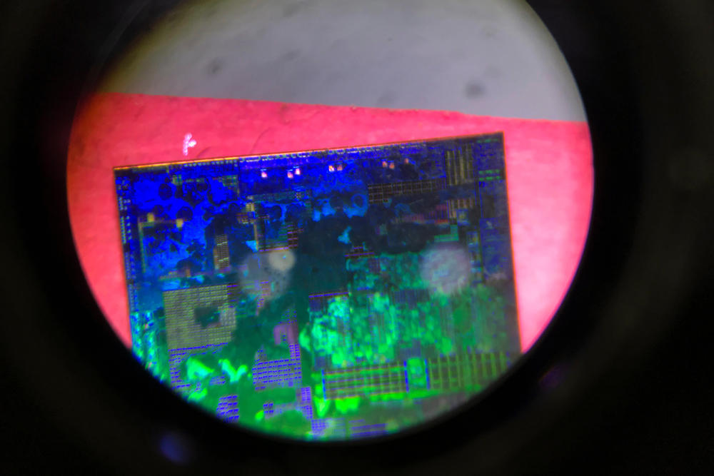 A Chinese microchip is seen through a microscope set up at the booth for the state-controlled Tsinghua Unigroup project during the 21st China Beijing International High-tech Expo in 2018. Tsinghua Unigroup said last December it had defaulted on paying the principal back on nearly $2.5 billion worth in bonds due to a 
