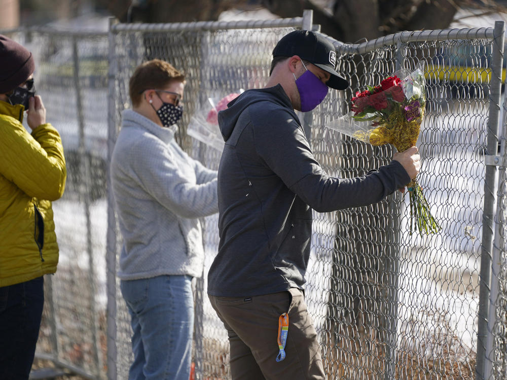 Kiefer Johnson places flowers Tuesday in a makeshift fence around the parking lot outside the King Soopers grocery store in Boulder, Colo., where 10 people were killed a day earlier.