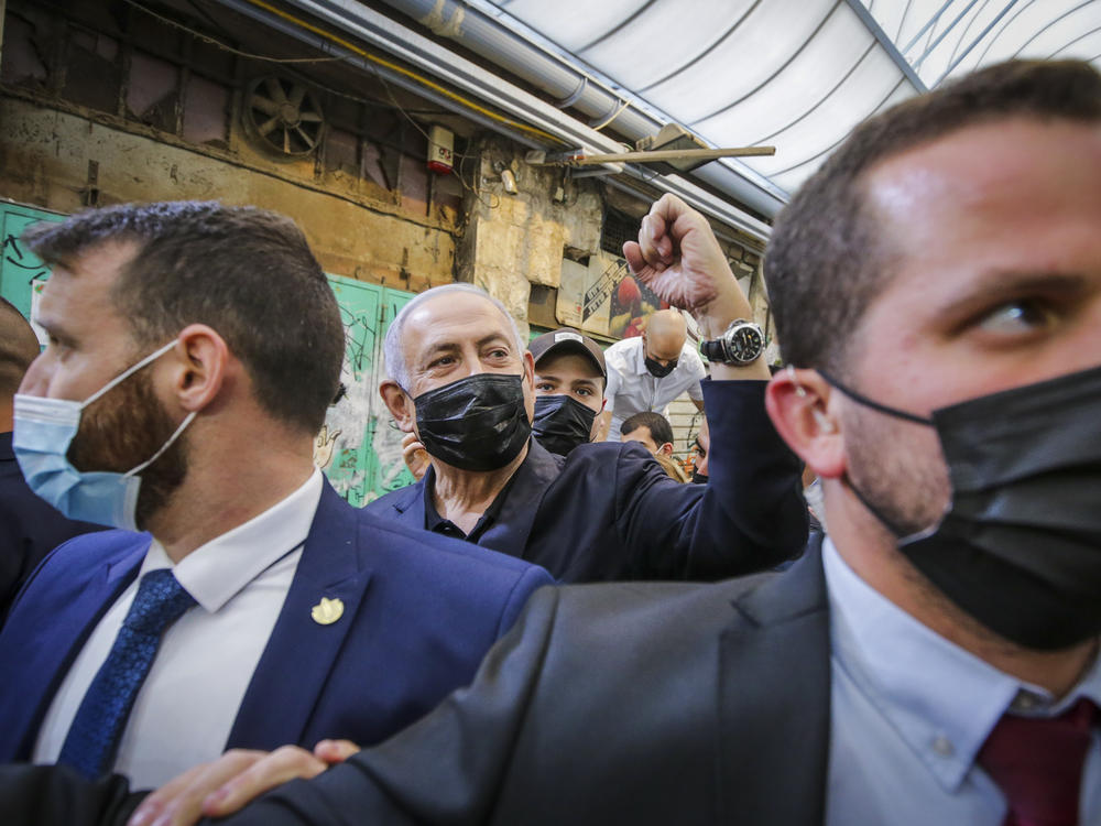 Israeli Prime Minister Benjamin Netanyahu, center, waves to supporters as he tours the Mahane Yehuda market while campaigning a day before national elections, in Jerusalem on Monday.