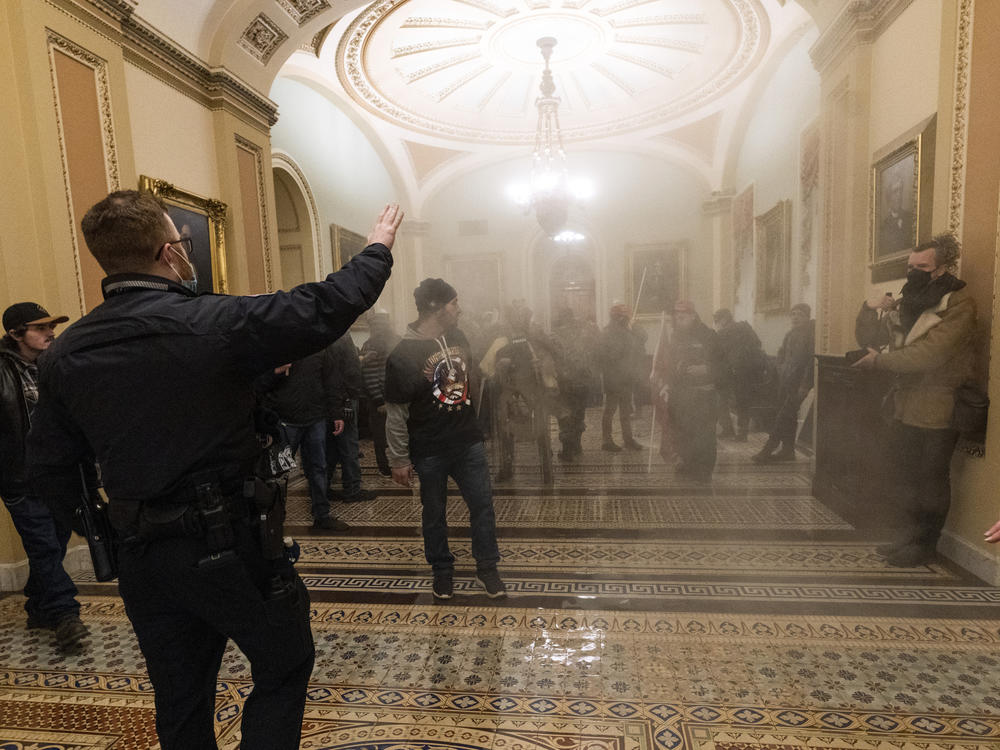 Smoke fills the walkway outside the Senate chamber as U.S. Capitol Police confront rioters inside the Capitol on Jan. 6.