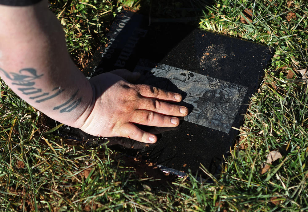 Cody places a stone on a distant family member's gravesite.