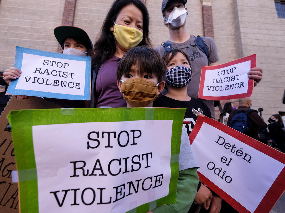 A family wearing face masks and holding signs take part in a rally 
